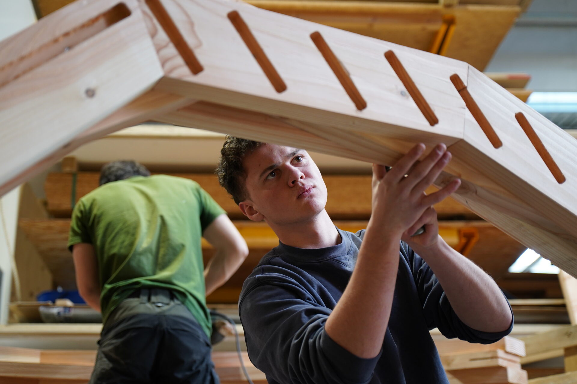 Etudiant sur une structure en bois dans la halle de l'ENSTIB